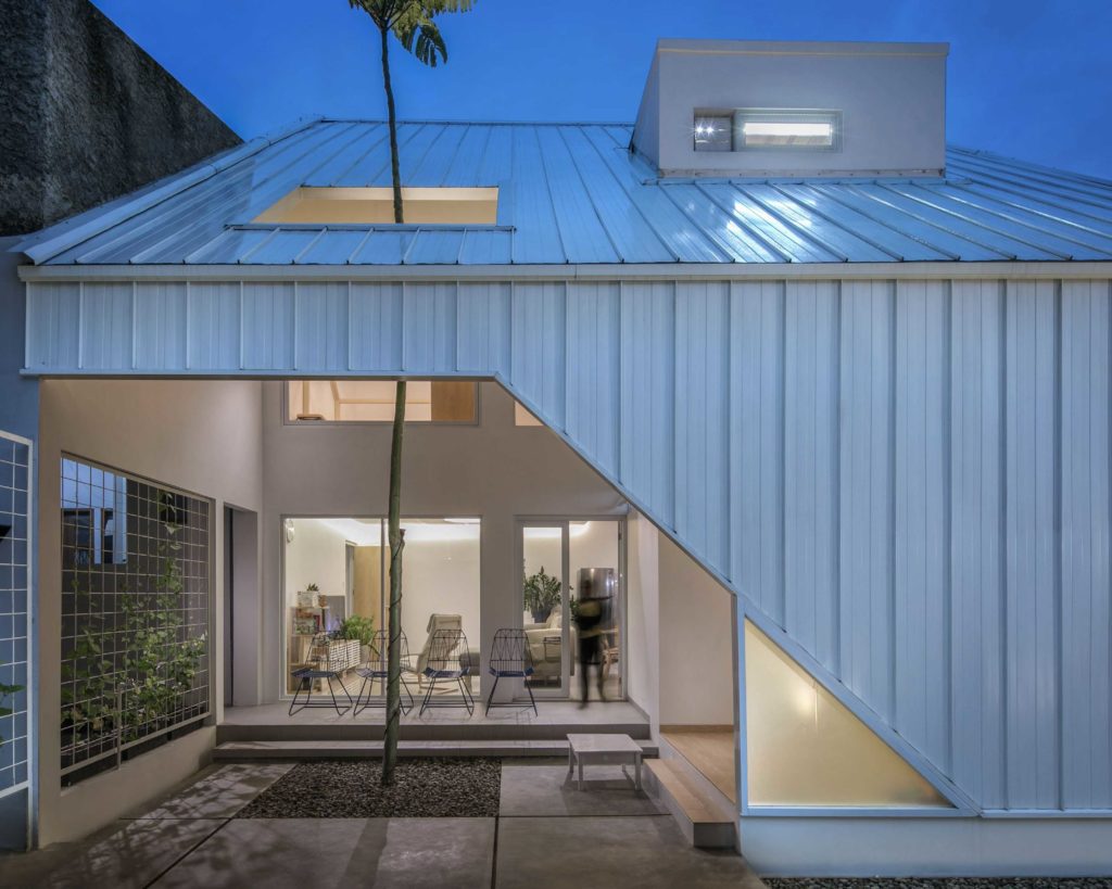 Bentuk geometris trapesium sebagai pembuka pada fasad rumah mungil dalam dominasi warna putih, karya Aaksen Responsible Aarchitecture via arsitag 